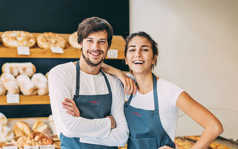 Zwei Bäckereifachverkäufer vor einem Regal mit Brot