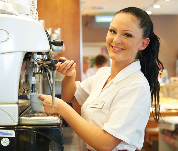 Frau steht am Kaffeeautomat