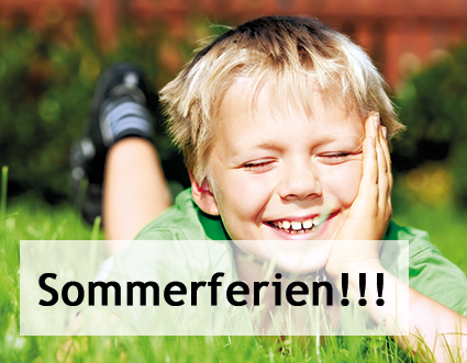 Lächelnder Junge liegt im Gras und freut sich über die Sommerferien