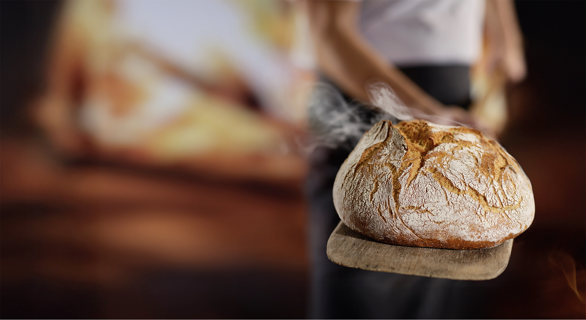 Bäcker hält ein Brot auf einem Brotschieber